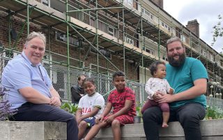 Mayor Perry with a father and his three children sitting outside a flower garden