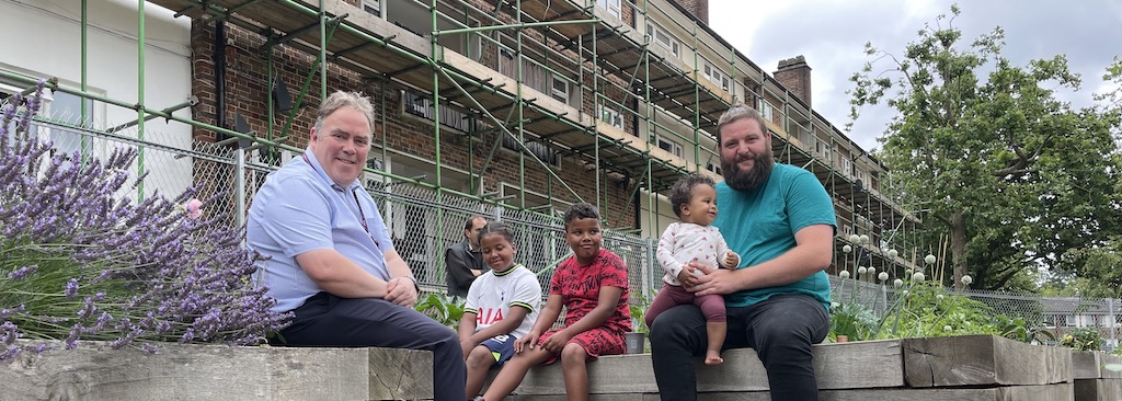 Mayor Perry with a father and his three children sitting outside a flower garden