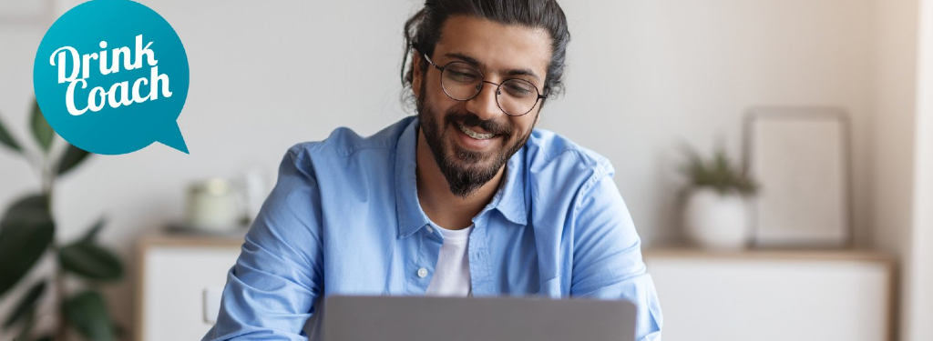 Man with glasses using a computer sitting next to the drink coach logo