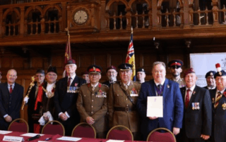 Mayor Perry stands with members of the military in Braithwaite Hall after signing the Armed Forces Covenant.