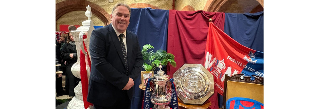 Mayor Perry standing next to the FA Cup and a shield in front of a Crystal Palace flag.